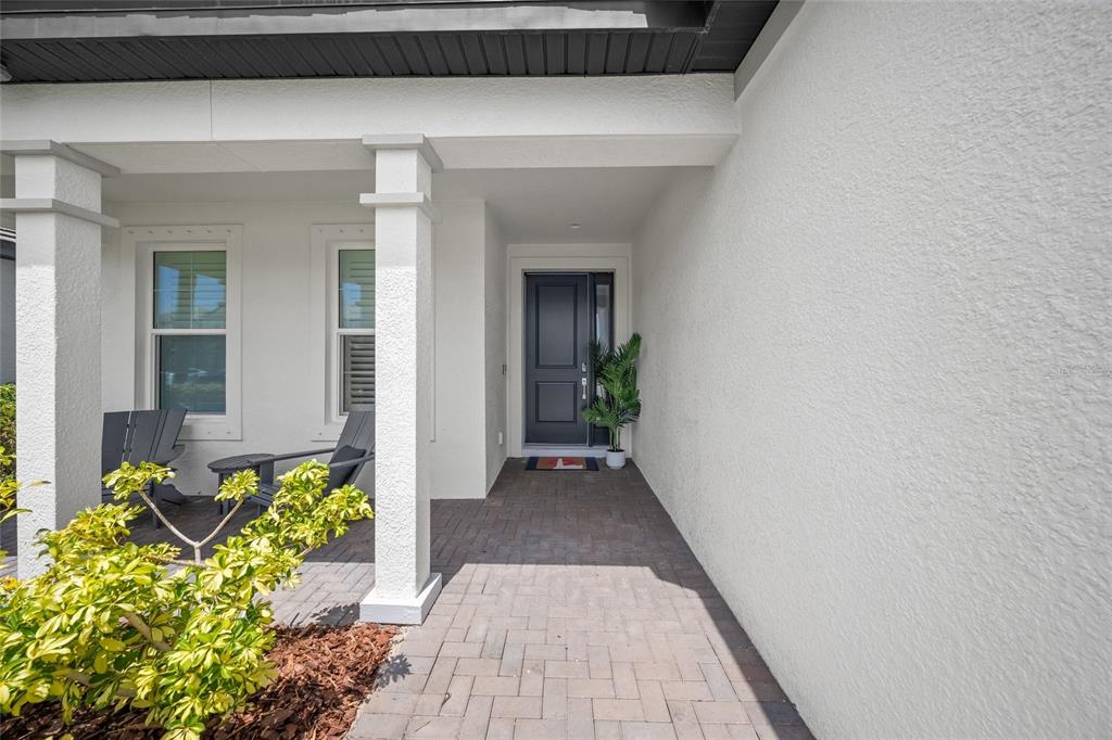 A front porch with a dark door, two chairs, and a paved walkway — 11504 APPLE TREE CIRCLE, BRADENTON, FL