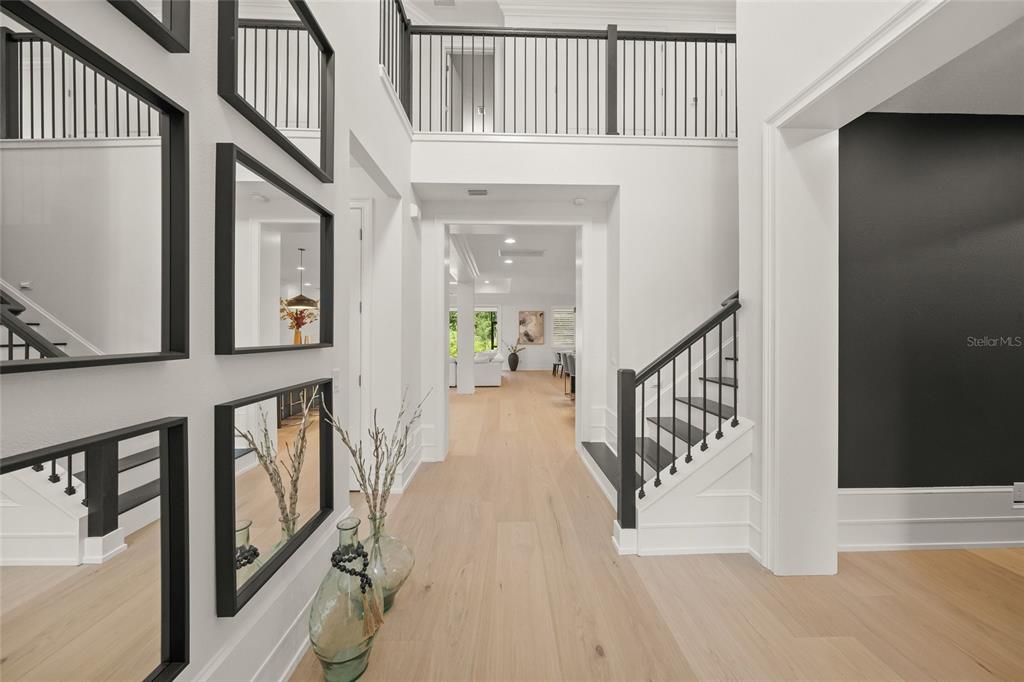 A bright foyer features light wood flooring, a black-railed staircase, and a gallery wall — 11504 APPLE TREE CIRCLE, BRADENTON, FL