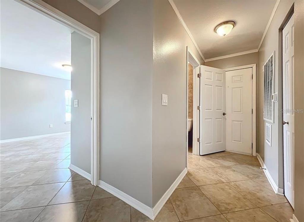 An interior view shows a tiled hallway leading to a doorway and a white door — 2513 GRASSY POINT DRIVE UNIT 107, LAKE MARY, FL