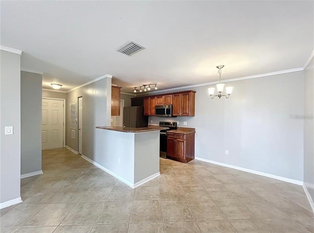A kitchen with wood cabinets and a breakfast bar opens into a dining area — 2513 GRASSY POINT DRIVE UNIT 107, LAKE MARY, FL