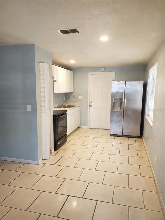 A kitchen with white cabinets, stainless steel appliances, and light-colored tile flooring — 5204 N 45TH STREET UNIT B, TAMPA, FL