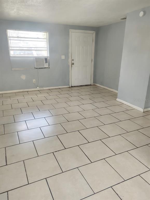 A room with light blue walls, white tile flooring, a window air conditioner, and a door — 5204 N 45TH STREET UNIT B, TAMPA, FL