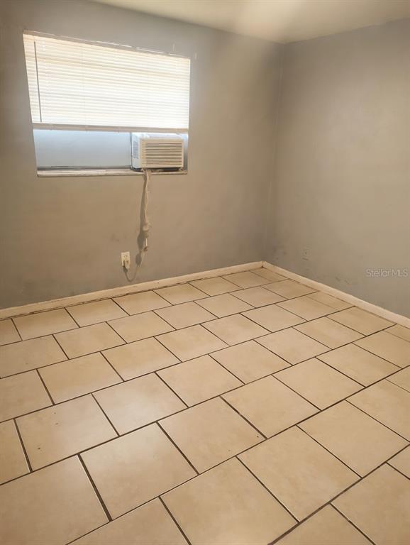 An empty room features light blue walls, beige tile flooring, and a window air conditioner — 5204 N 45TH STREET UNIT B, TAMPA, FL