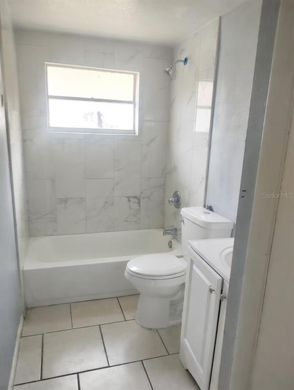 A bathroom features a white bathtub, a toilet, a vanity, and white marble-look wall tiles — 5204 N 45TH STREET UNIT B, TAMPA, FL