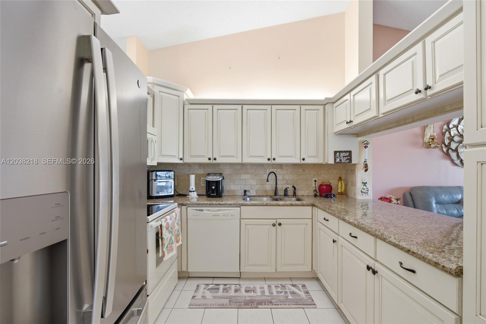 A kitchen features off-white cabinets, granite countertops, stainless steel appliances, and a tiled floor — 104 Freedom Ct # 104, Deerfield Beach FL 33442, DEERFIELD BEACH, FL