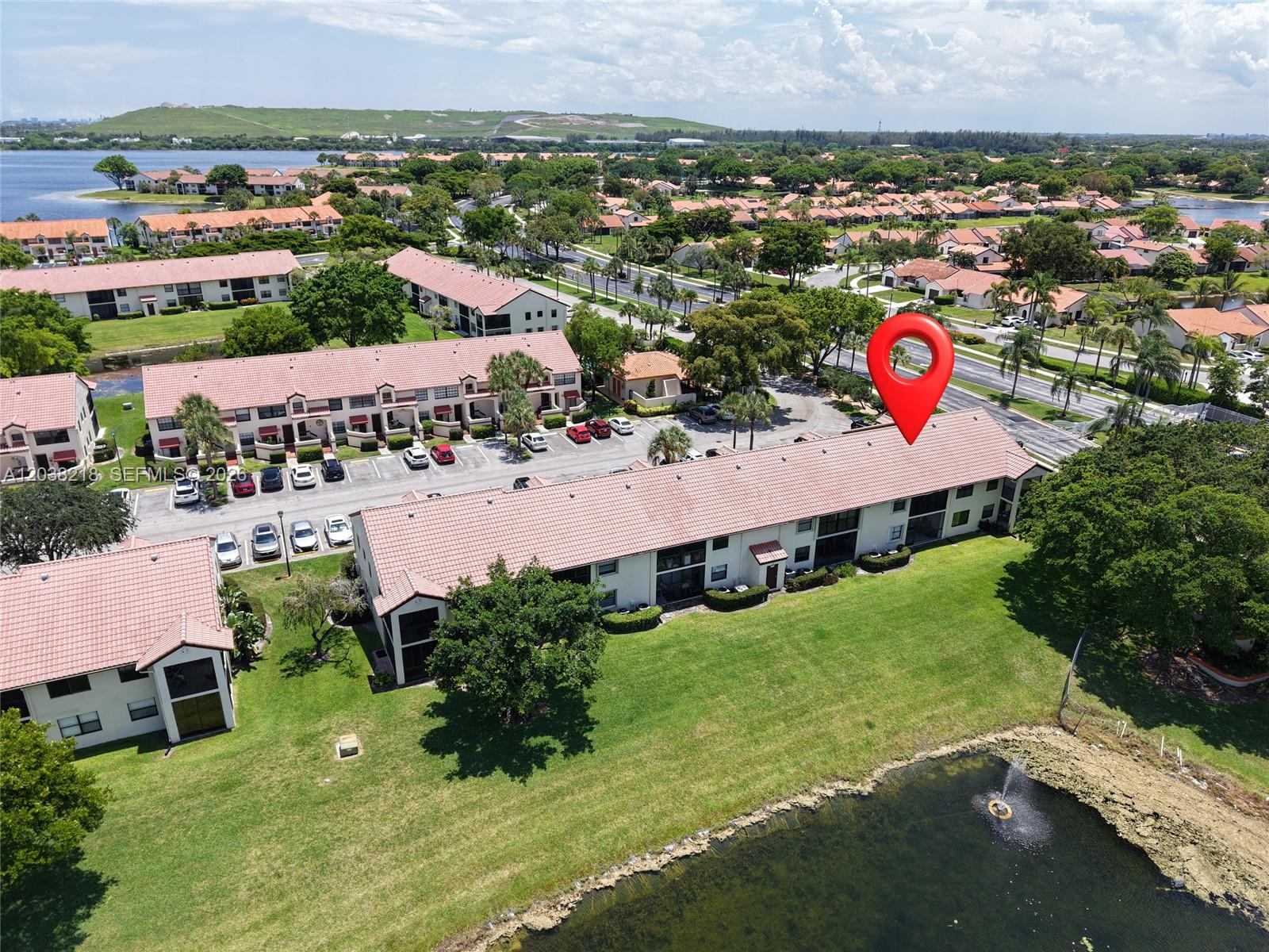 An aerial view shows a multi-story residential building with a red tile roof near water — 104 Freedom Ct # 104, Deerfield Beach FL 33442, DEERFIELD BEACH, FL