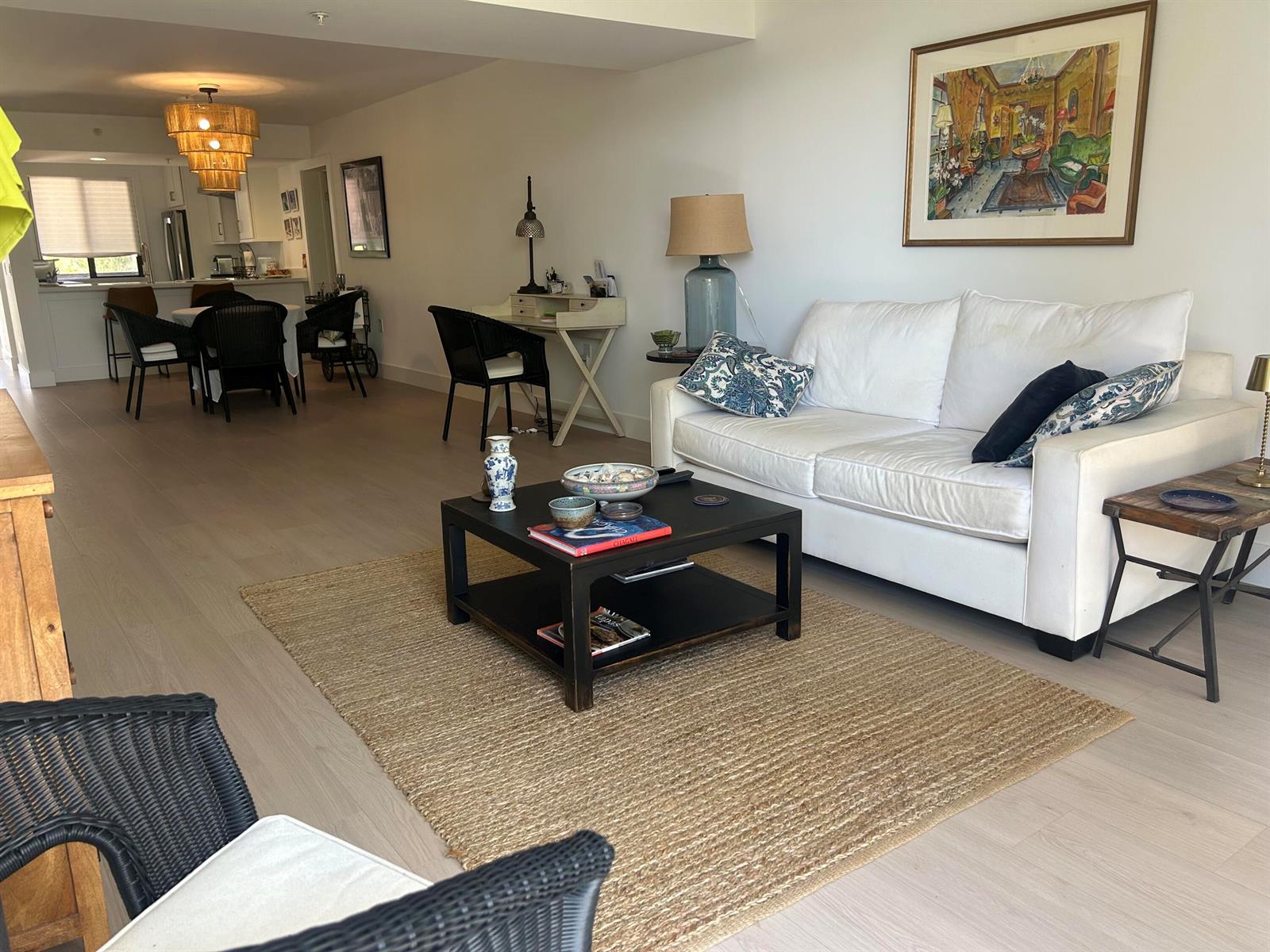 A living room with a white sofa, black coffee table, and dining area in the background — 1901 Marina Isle Way # 302, Jupiter FL 33477, JUPITER, FL