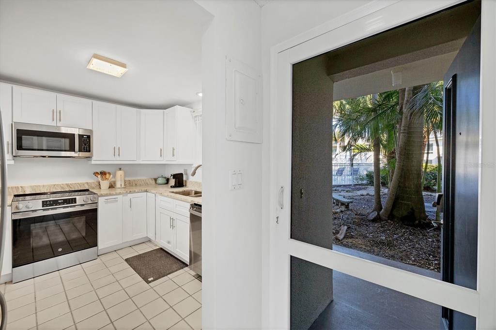 A kitchen with white cabinets and stainless steel appliances opens to a view of trees — 500 S WASHINGTON DRIVE UNIT 3A, SARASOTA, FL