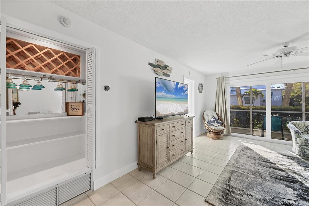 A living room features a built-in wine rack, a television on a dresser, and tile flooring — 500 S WASHINGTON DRIVE UNIT 3A, SARASOTA, FL
