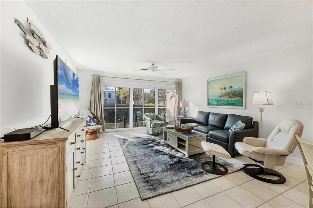 A living room features a dark leather sofa, a patterned area rug, and tile flooring — 500 S WASHINGTON DRIVE UNIT 3A, SARASOTA, FL