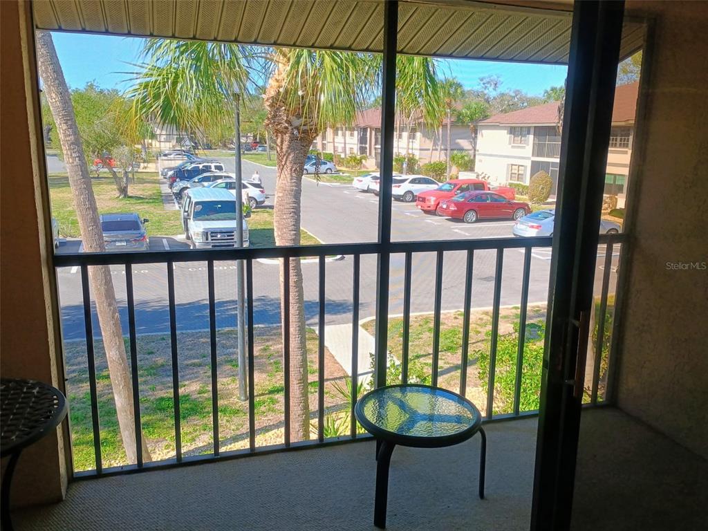 A screened-in balcony overlooks a parking lot with several cars and palm trees — 19505 QUESADA AVENUE UNIT CC205, PORT CHARLOTTE, FL