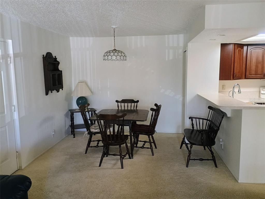 A dining area with a wooden table, chairs, a bench, and a hanging pendant light — 19505 QUESADA AVENUE UNIT CC205, PORT CHARLOTTE, FL