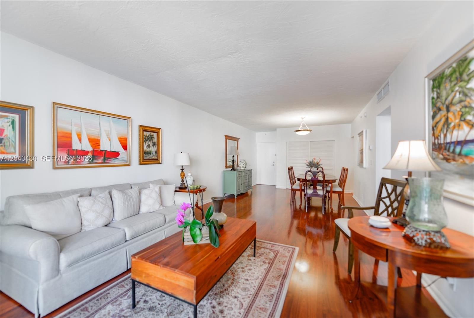 A living and dining room area features hardwood floors, a light sofa, and wall art — 3000 S Ocean Dr # 514, Hollywood FL 33019, HOLLYWOOD, FL
