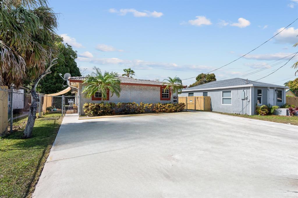 A large concrete driveway sits in front of two single-story residential buildings with palm trees — 617 NW 15th Avenue, Pompano Beach FL 33069, POMPANO BEACH, FL