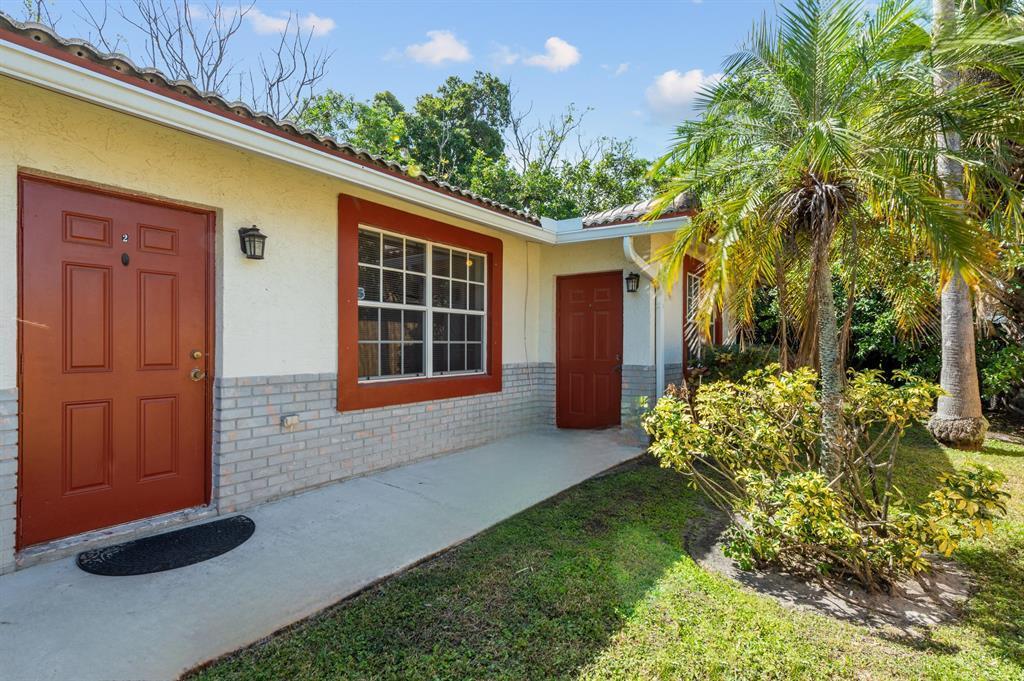 The exterior of a single-story building features two red doors, a window, and landscaping — 617 NW 15th Avenue, Pompano Beach FL 33069, POMPANO BEACH, FL