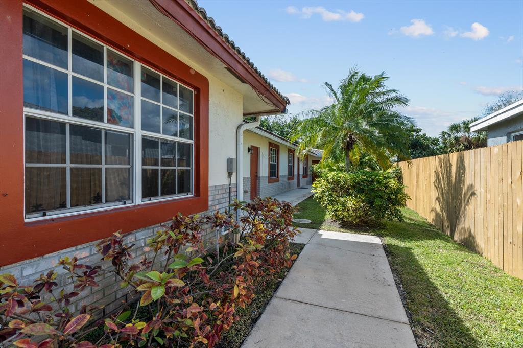 A concrete walkway leads along the side of a house with red trim and landscaping — 617 NW 15th Avenue, Pompano Beach FL 33069, POMPANO BEACH, FL