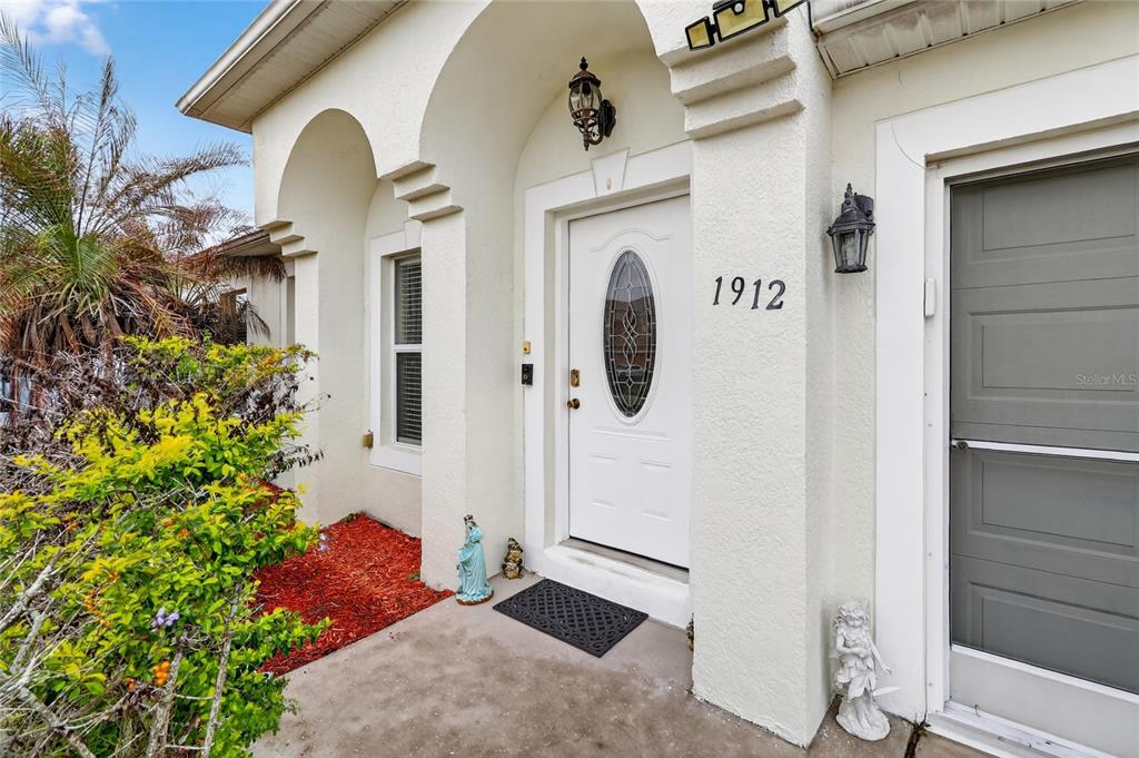 The exterior entrance features a white front door with an oval window and house numbers — 1912 LAKEVIEW PLACE, KISSIMMEE, FL