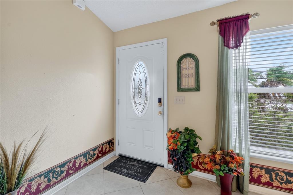 An entryway features a white front door, tile flooring, and decorative wallpaper borders — 1912 LAKEVIEW PLACE, KISSIMMEE, FL