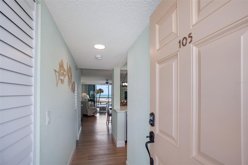 An open door reveals a hallway leading to a living area with a beach view — 18304 GULF BOULEVARD UNIT 105, REDINGTON SHORES, FL