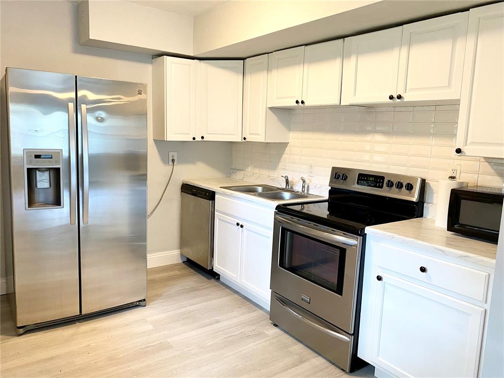 A kitchen features white cabinets, stainless steel appliances, and light-colored countertops — 2343 8TH STREET S, ST PETERSBURG, FL