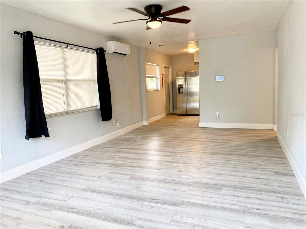 A living room with light wood-look flooring, a ceiling fan, and an adjacent kitchen area — 2343 8TH STREET S, ST PETERSBURG, FL