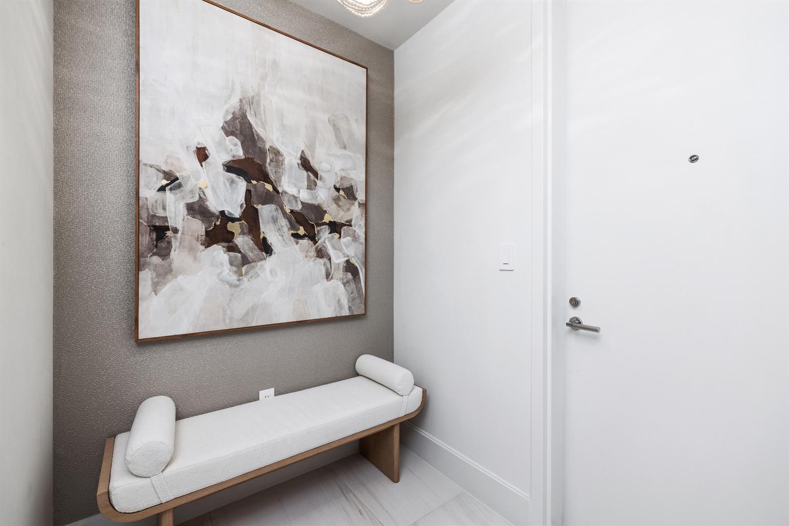 A modern entryway features a white bench, textured gray wallpaper, and a large abstract painting — 305 Briny Avenue # 804, Pompano Beach FL 33062, POMPANO BEACH, FL