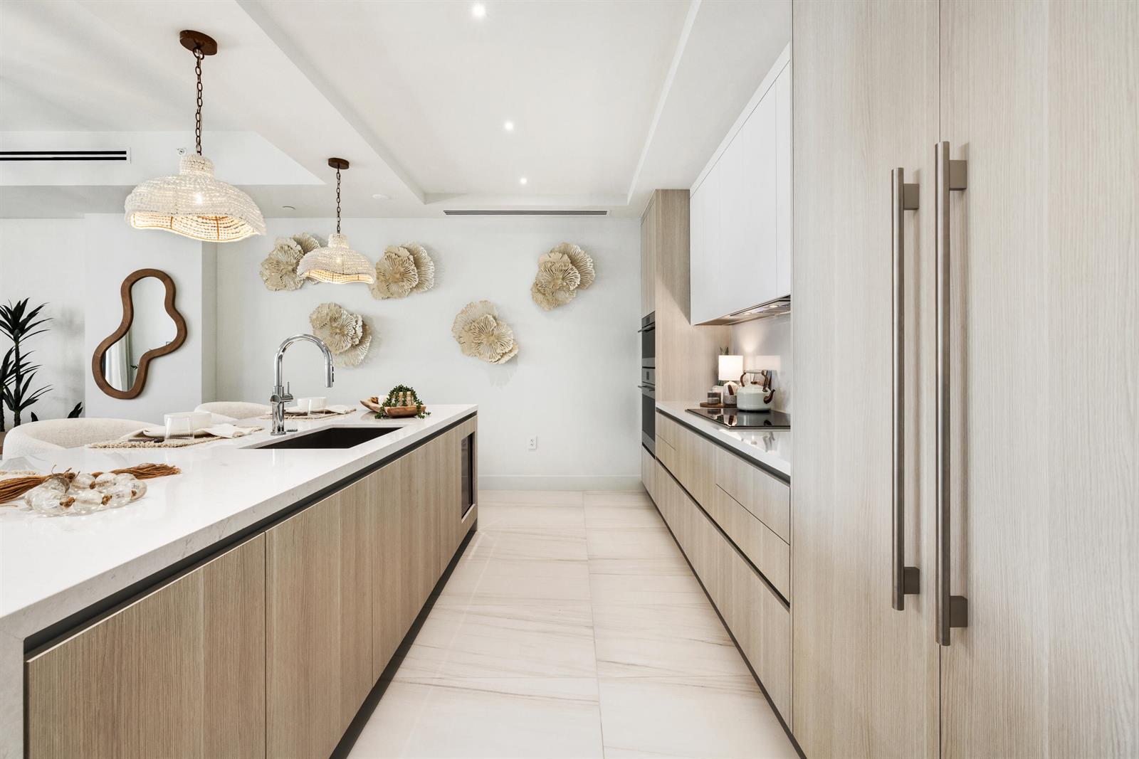 A modern kitchen features light wood cabinetry, a white stone island, and decorative wall art — 305 Briny Avenue # 804, Pompano Beach FL 33062, POMPANO BEACH, FL