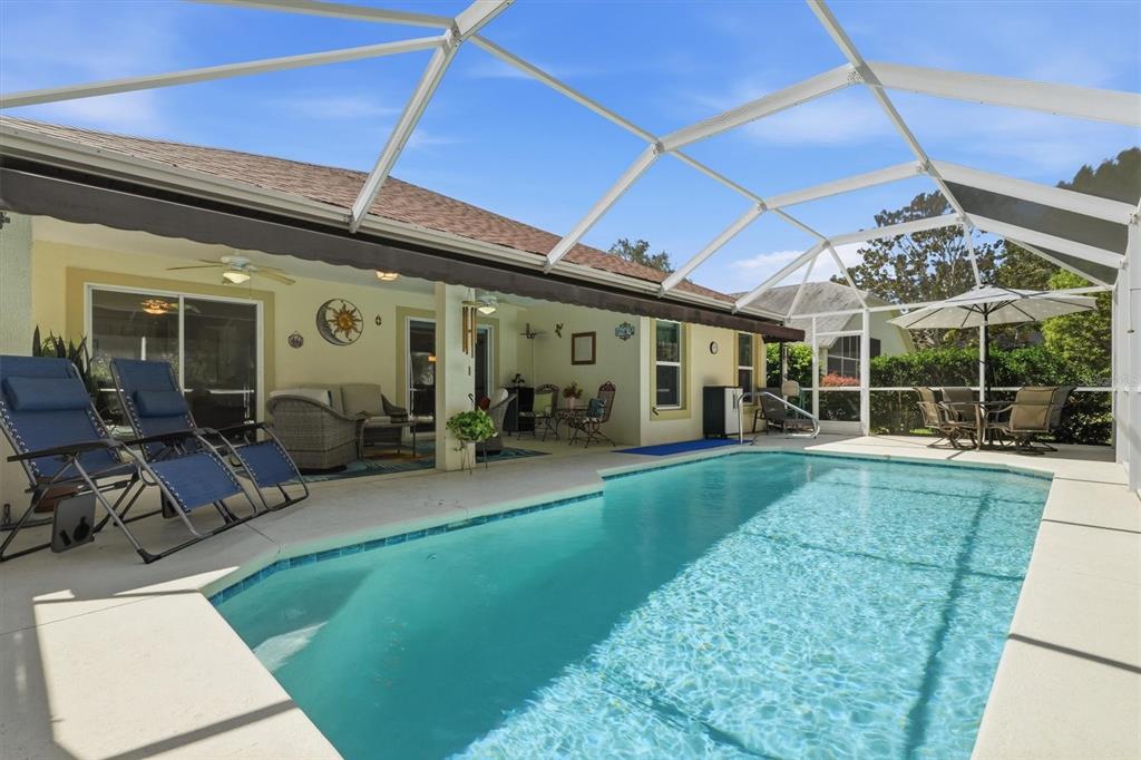 A screened-in patio features a swimming pool, lounge chairs, and outdoor dining furniture — 6133 LANDINGS BOULEVARD, LADY LAKE, FL