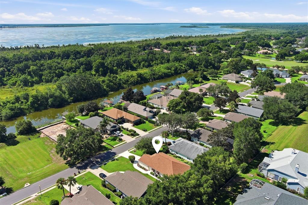 An aerial view shows a suburban neighborhood with houses, a canal, and a large lake — 6133 LANDINGS BOULEVARD, LADY LAKE, FL