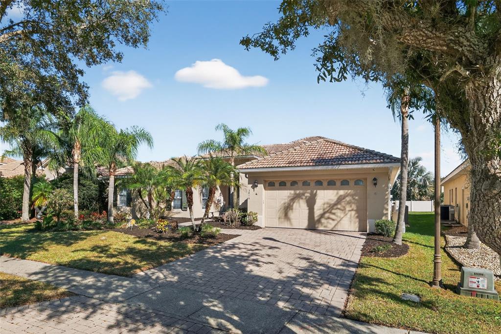 A single-story house with a tiled roof, beige stucco exterior, and a paved driveway — 3816 EAGLE ISLE CIRCLE, KISSIMMEE, FL
