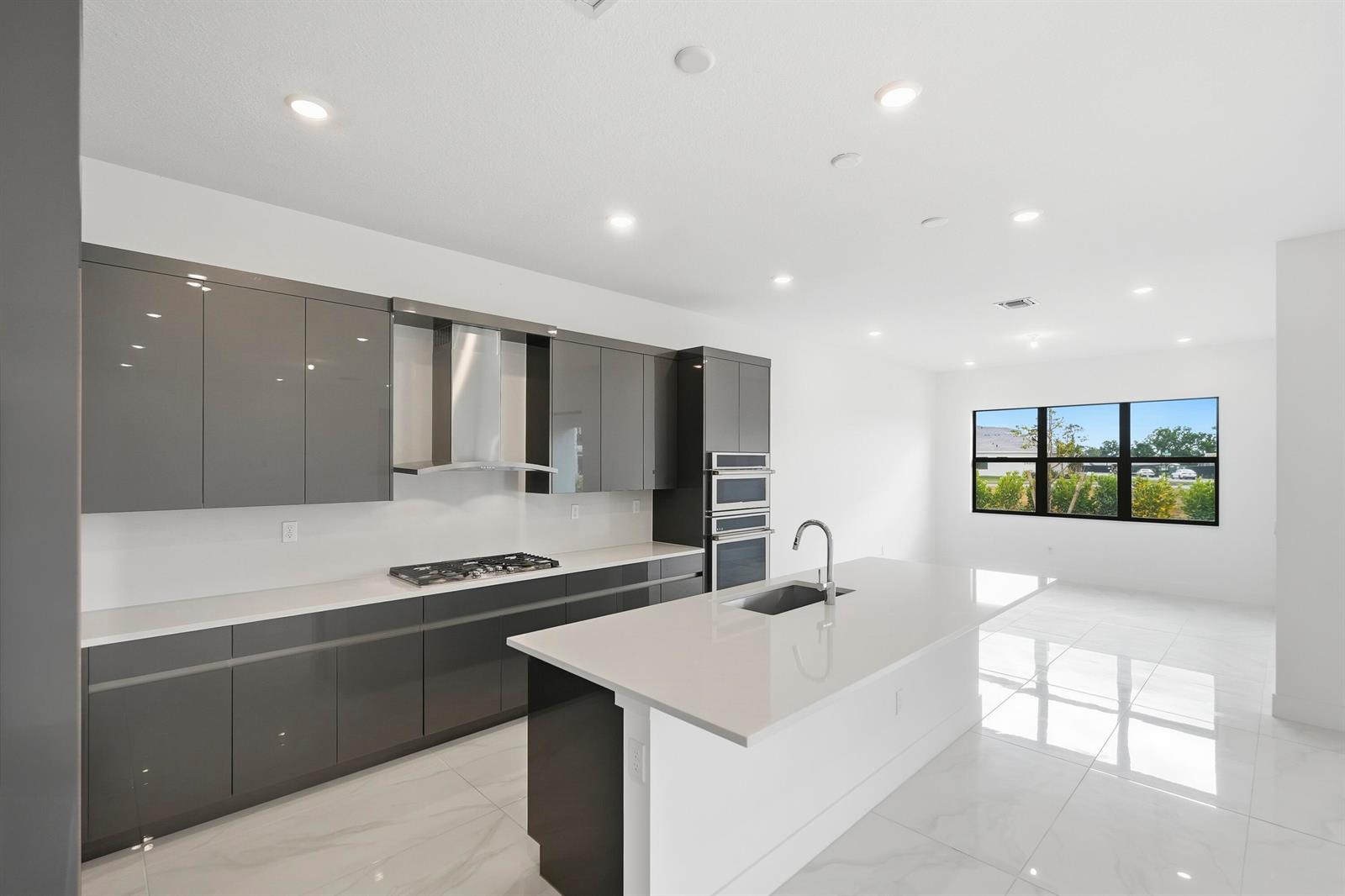 A modern kitchen features gray high-gloss cabinetry, white quartz countertops, and a central island — 7593 Bridle Trail Way, Lake Worth FL 33449, LAKE WORTH, FL