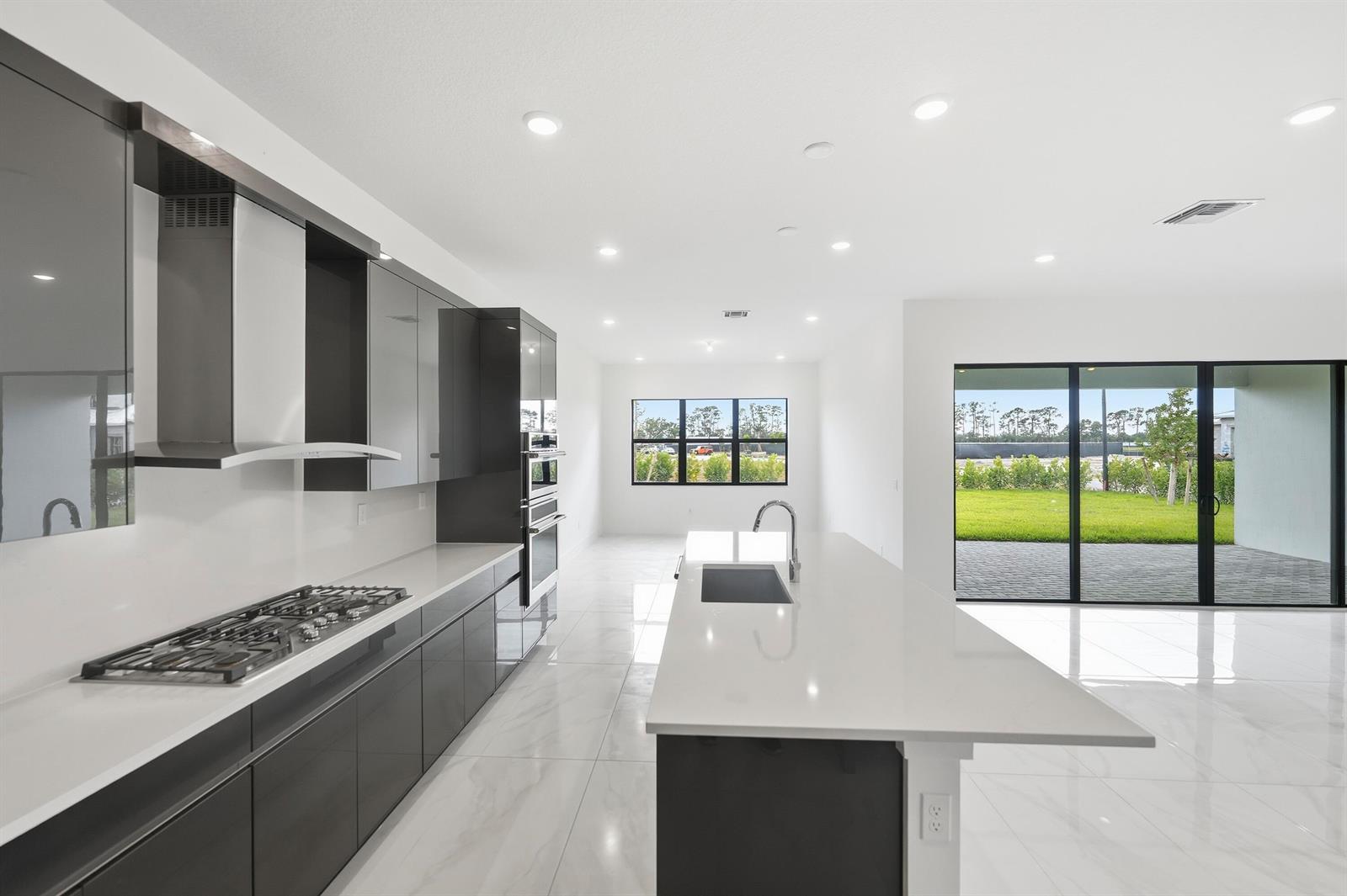 A modern kitchen features dark gray cabinetry, white countertops, a center island, and tile flooring — 7593 Bridle Trail Way, Lake Worth FL 33449, LAKE WORTH, FL