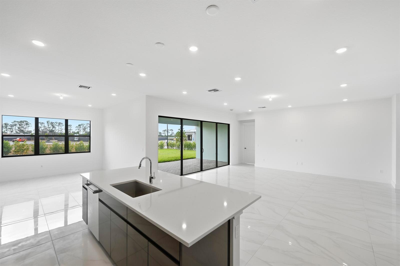 A modern kitchen island with a sink overlooks an open living area with tile floors — 7593 Bridle Trail Way, Lake Worth FL 33449, LAKE WORTH, FL