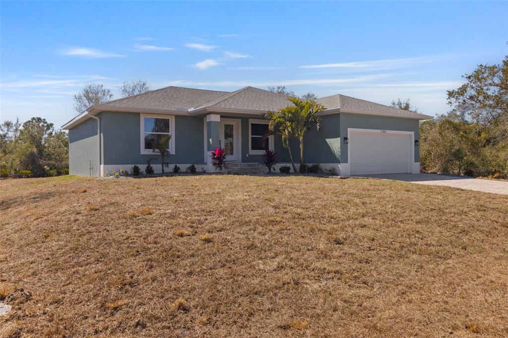 A single-story house with a blue-grey exterior, a two-car garage, and a dry lawn — 17203 CHASE AVENUE, PORT CHARLOTTE, FL