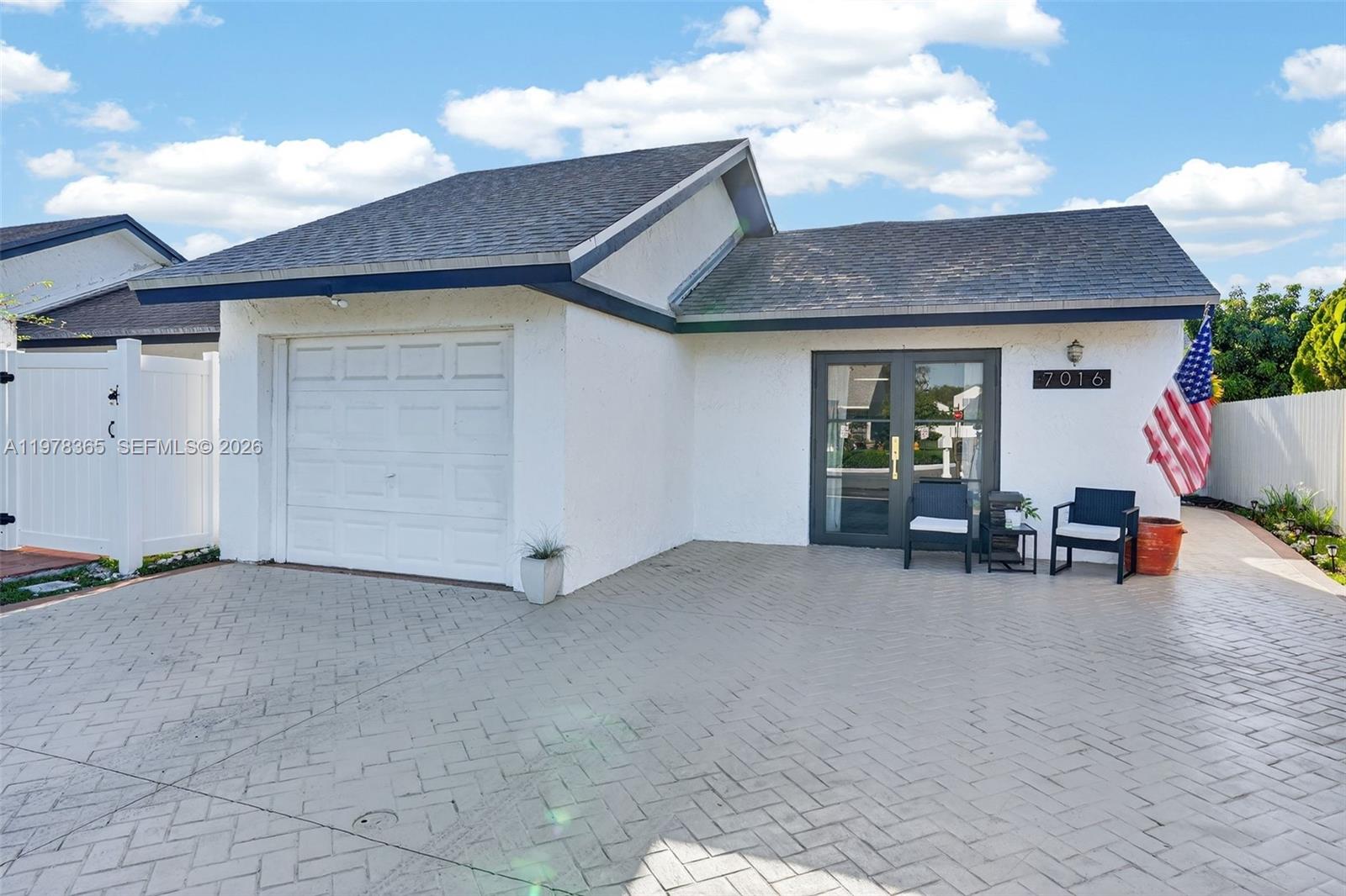 A white house with a garage, a paved driveway, and a front entrance with glass doors — 7016 SW 103rd Pl, Miami FL 33173, MIAMI, FL