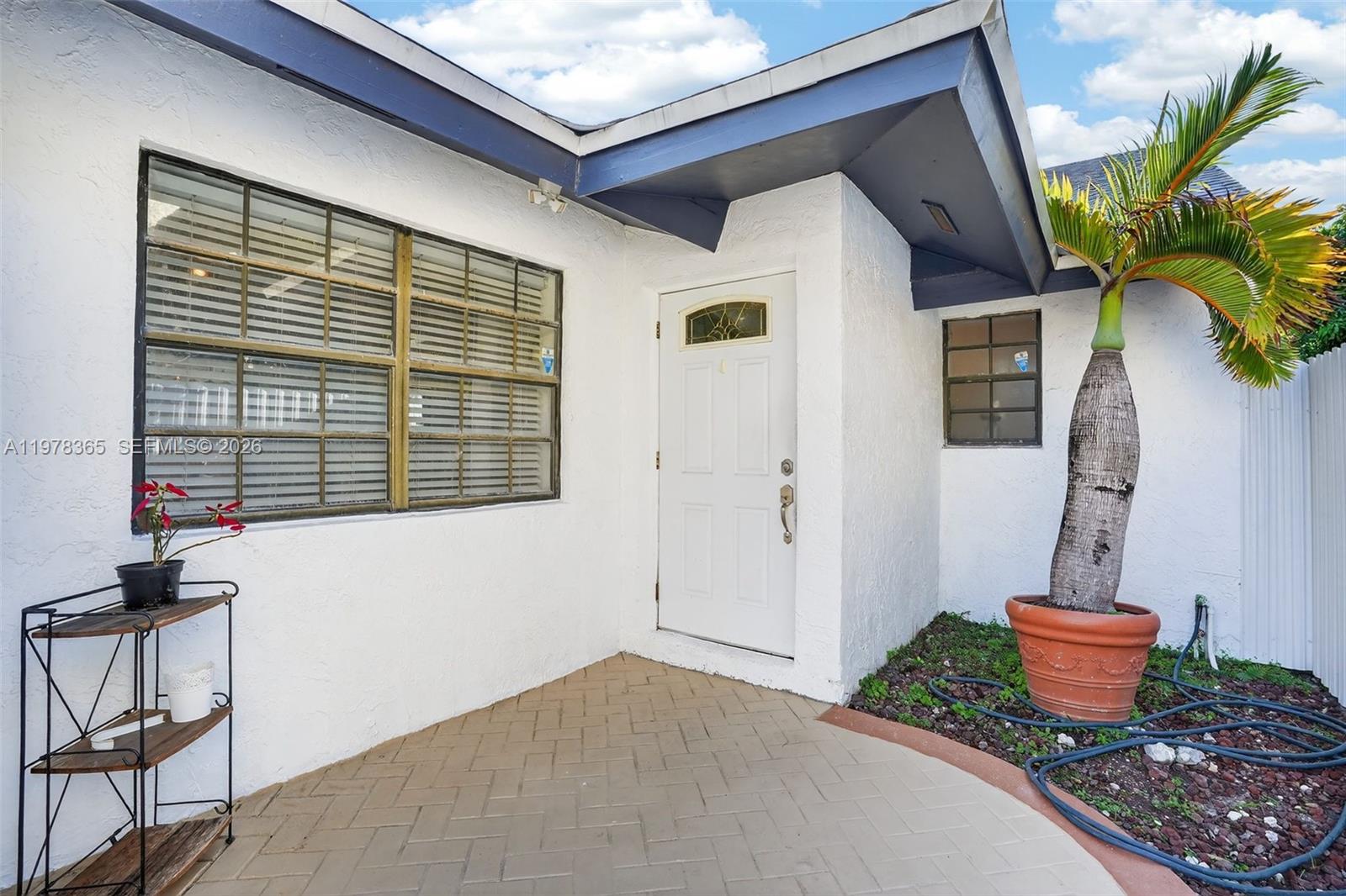 A white house exterior features a front door, a large window, and a potted palm — 7016 SW 103rd Pl, Miami FL 33173, MIAMI, FL