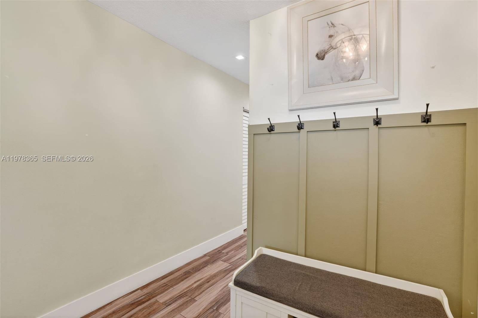 This entryway features a wooden bench, wall-mounted coat hooks, and a framed horse print — 7016 SW 103rd Pl, Miami FL 33173, MIAMI, FL