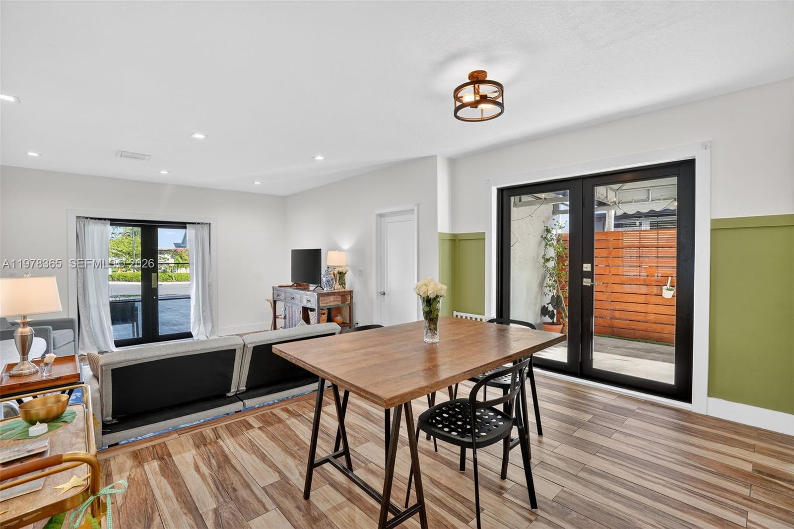 A dining area with a wooden table and black chairs sits beside a living room — 7016 SW 103rd Pl, Miami FL 33173, MIAMI, FL