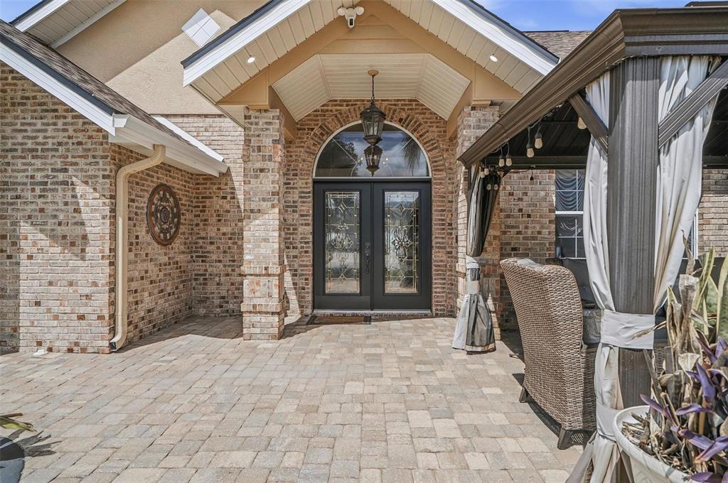 A brick house exterior features a covered entryway with a double door and stone pavers — 11 BANNERWOOD LANE, PALM COAST, FL