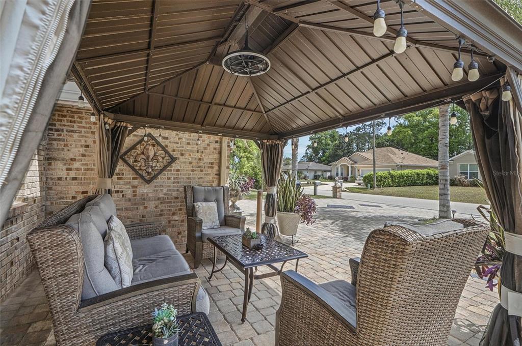 A covered outdoor patio features wicker furniture, a metal gazebo roof, and brick walls — 11 BANNERWOOD LANE, PALM COAST, FL
