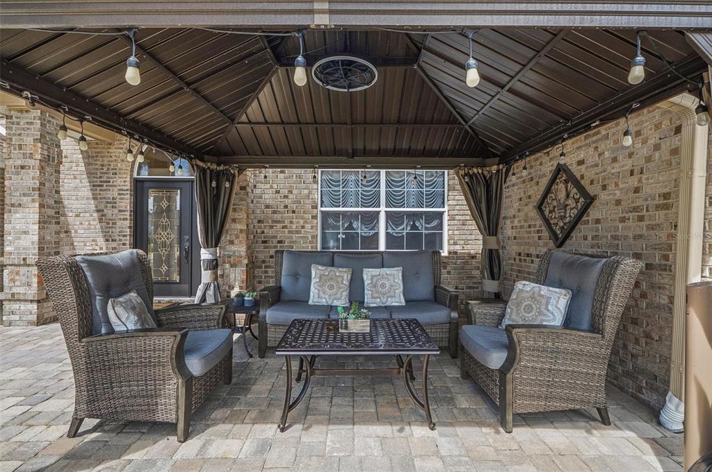 A covered outdoor patio features wicker furniture, a metal gazebo roof, and brick walls — 11 BANNERWOOD LANE, PALM COAST, FL