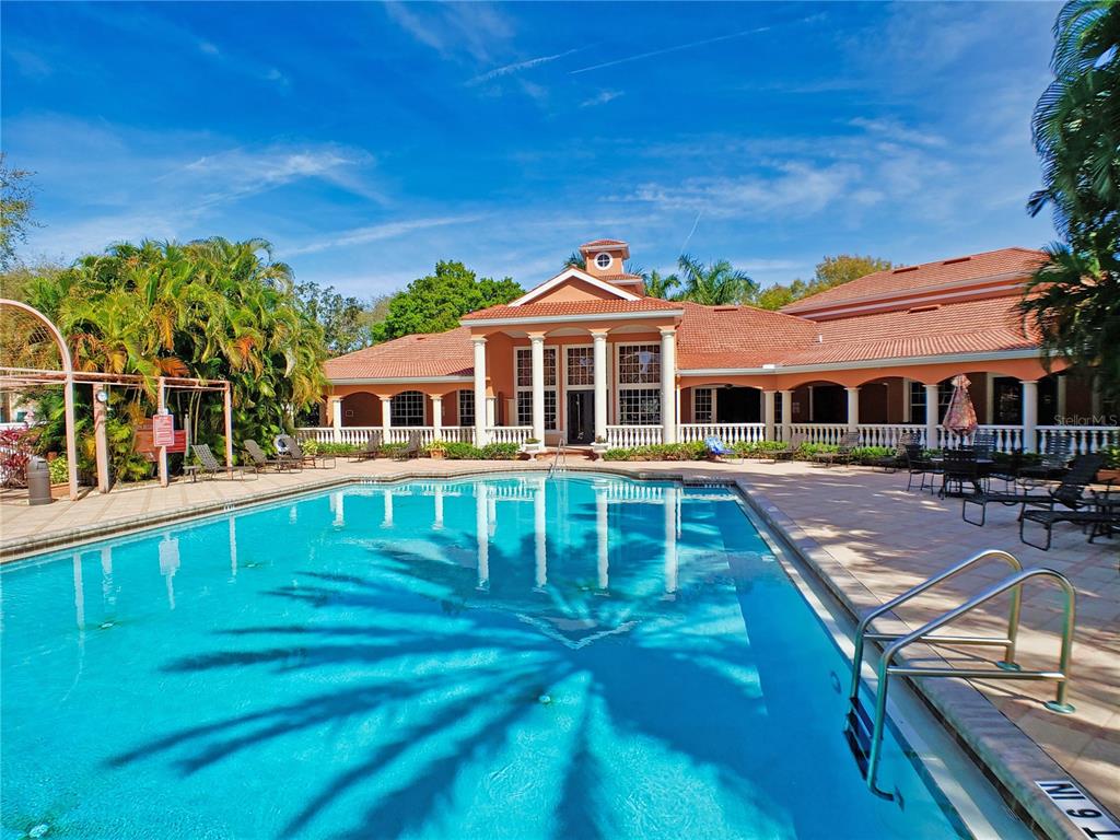 A swimming pool sits in front of a large, single-story clubhouse with a tiled roof — 4118 CENTRAL SARASOTA PARKWAY UNIT 1628, SARASOTA, FL
