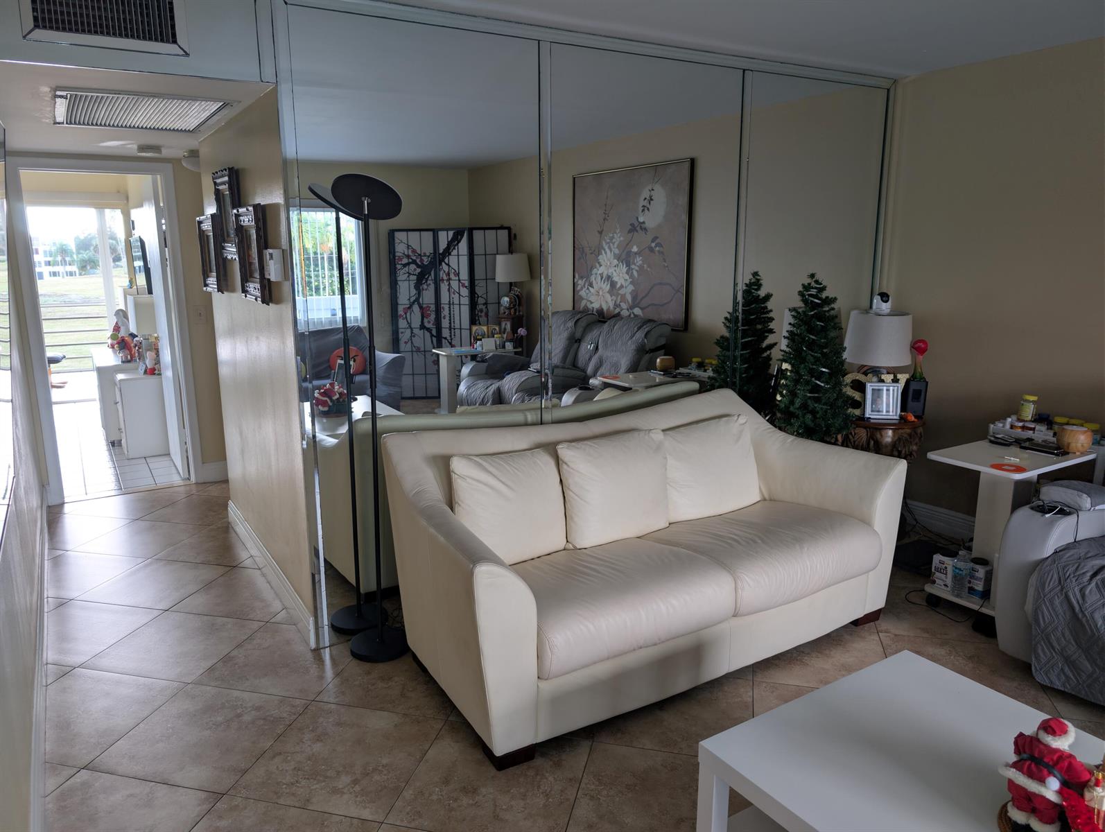 A living room features a white leather sofa, tiled floors, and a large mirrored wall — 3036 Ventnor H # 3036, Deerfield Beach FL 33442, DEERFIELD BEACH, FL