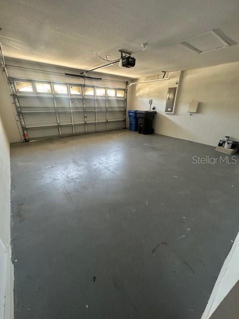 An empty garage with a concrete floor, a sectional door, and two trash bins — 11121 KEMPTON VISTA DRIVE, RIVERVIEW, FL