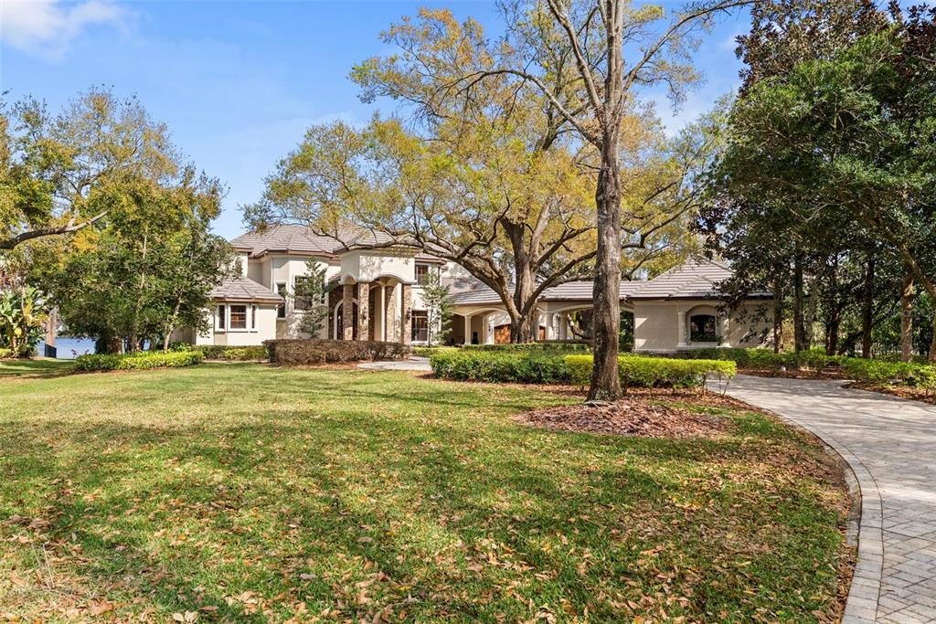 A large two-story house with a stone-pillared entryway and a covered driveway leading to garages — 9902 MENANDER WOOD COURT, ODESSA, FL