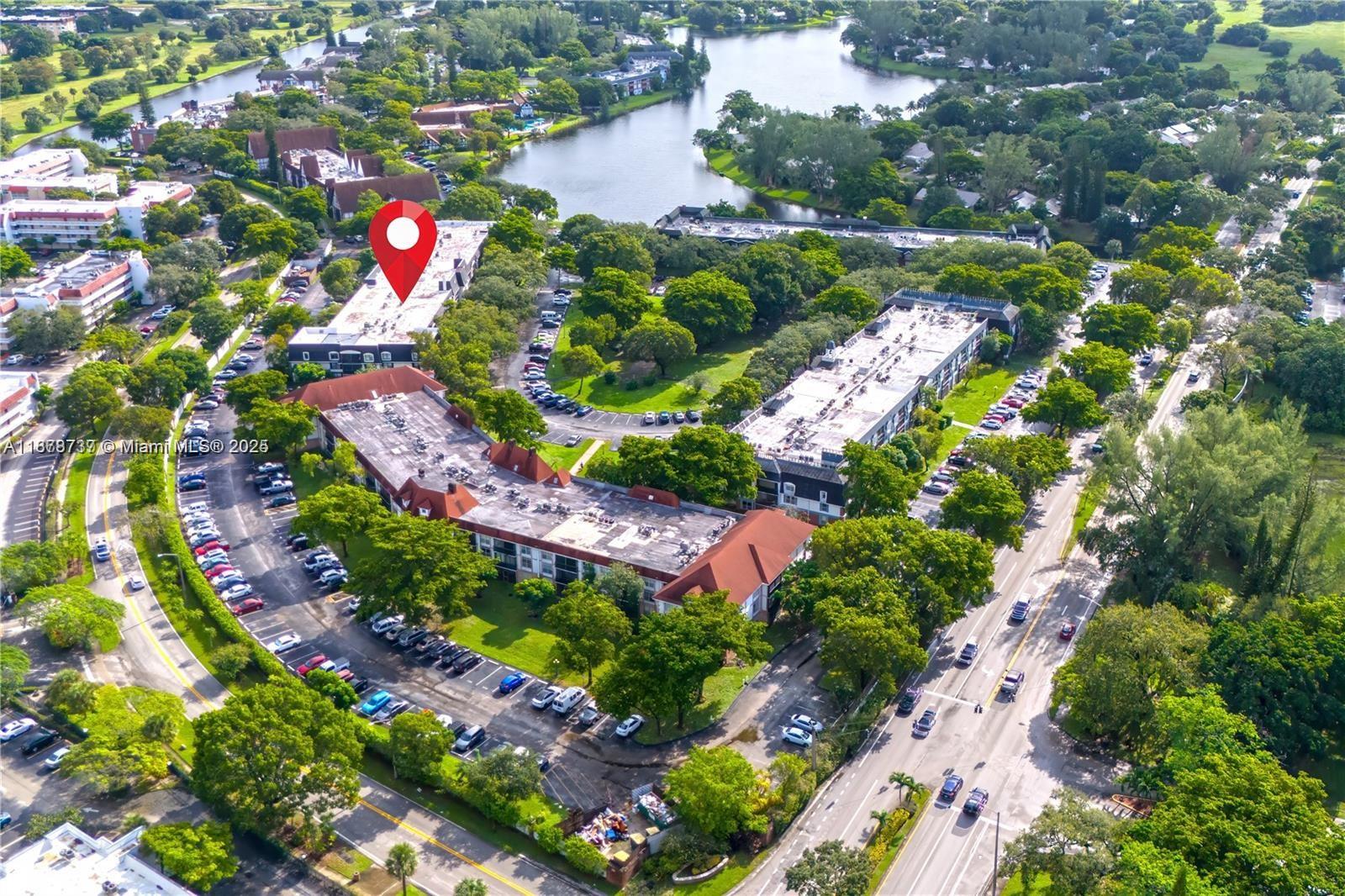 An aerial view shows multi-story apartment buildings surrounded by parking lots, trees, and a lake — 3680 Inverrary Dr # 3J, Lauderhill FL 33319, LAUDERHILL, FL