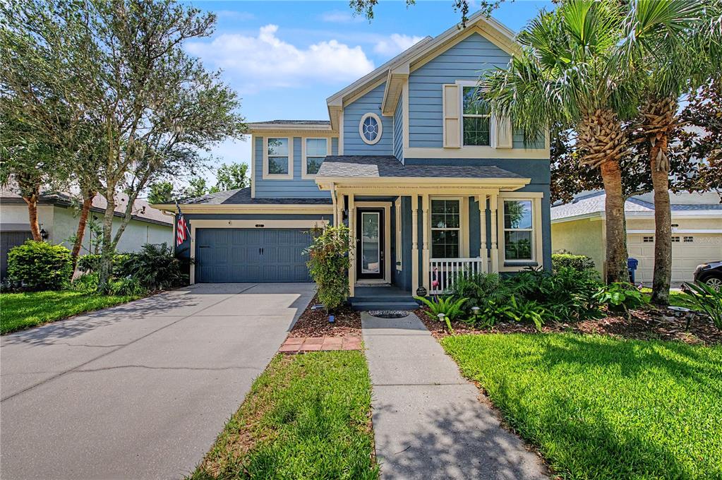 A two-story blue house with a front porch, a two-car garage, and a concrete driveway — 8137 LAGERFELD DRIVE, LAND O LAKES, FL