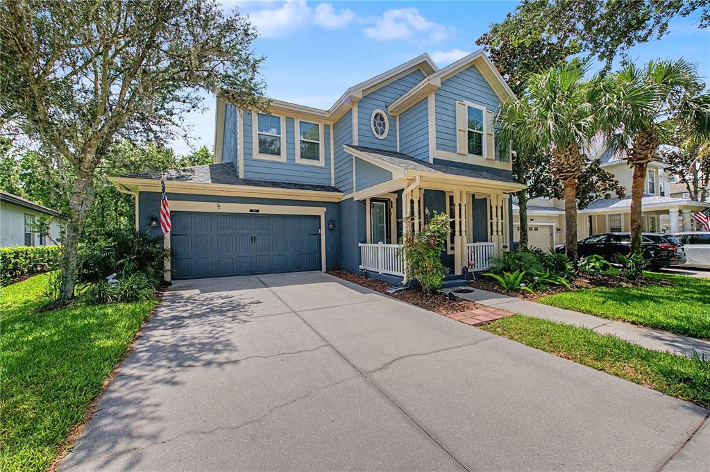 A two-story blue house with a two-car garage, front porch, and a concrete driveway — 8137 LAGERFELD DRIVE, LAND O LAKES, FL