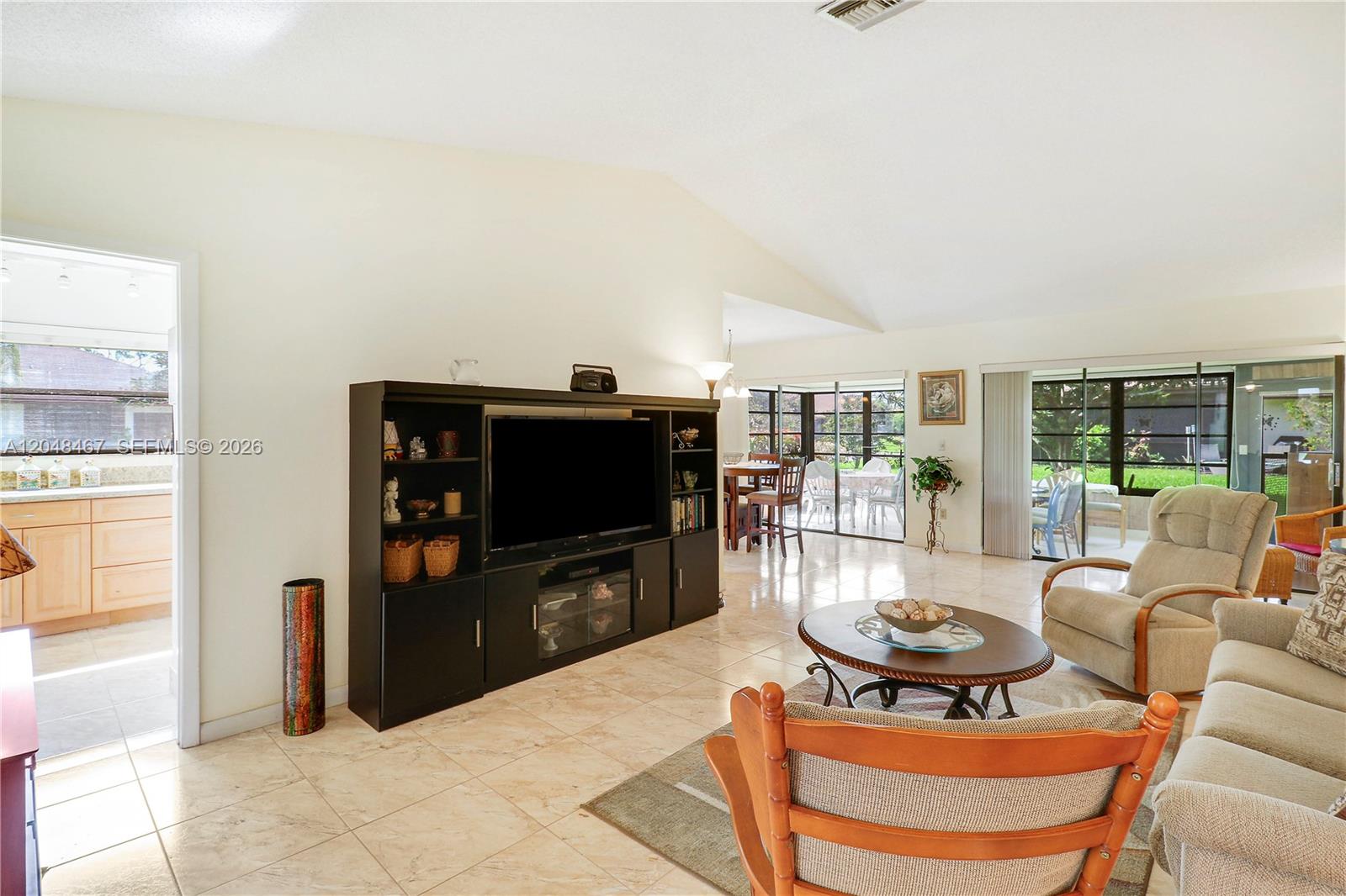A living room features tile floors, a large entertainment center, and sliding glass doors — 3449 Shadow Wood Dr, Green Acres FL 33463, GREEN ACRES, FL