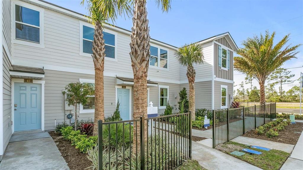 A two-story townhouse exterior with light siding, blue doors, and a black metal fence — 296 PALMETTO RIDGE ROAD, ST AUGUSTINE, FL
